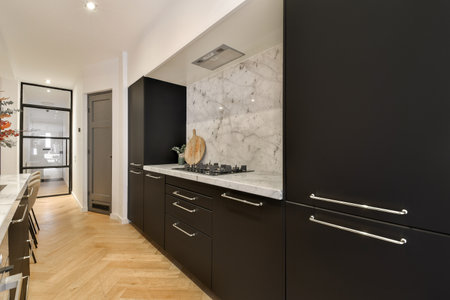 a modern kitchen with black cabinets and marble counter tops on the island in the center of the room is wooden flooringの写真素材