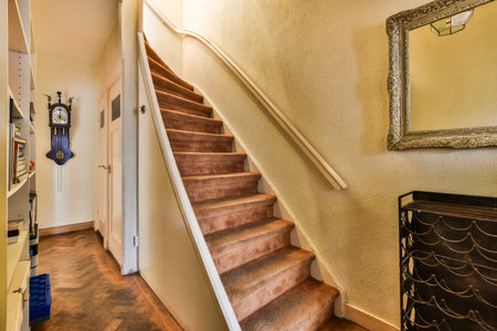 a stairway way in a house with wood flooring and white trim on the wall, framed by an ornate mirrorの写真素材