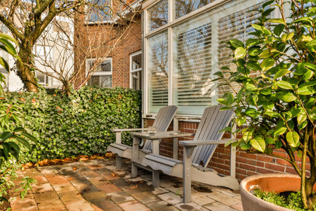 an outside area with a bench and potted plant on the ground in front of a brick wall that has been painted whiteの写真素材