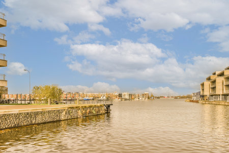 a body of water with buildings on both sides and clouds in the sky above it, as seen from a moving boatの写真素材