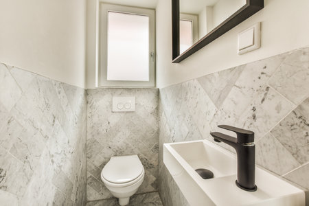 a bathroom with marble tiles on the walls, and a white toilet in the corner next to it is a mirror