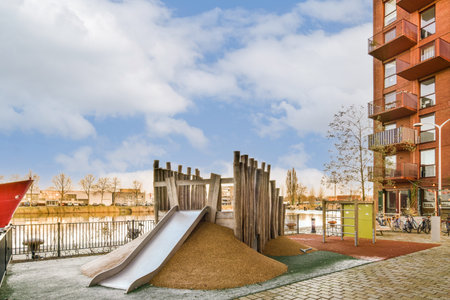 an outdoor play area with a slide in the middle and people playing on the other side of the playgroundsの写真素材