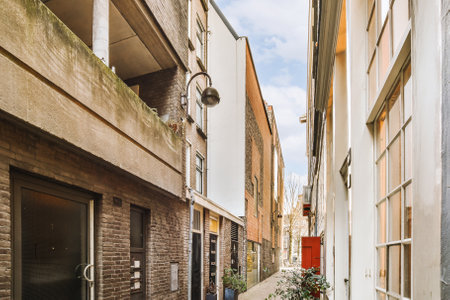a narrow street with buildings in the background and a red door on the right hand side that leads to...