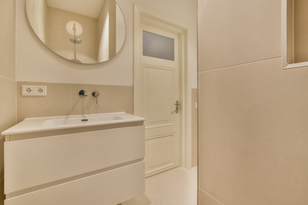 a bathroom with a sink, mirror and toilet paper on the wall next to it is a large white cabinetの写真素材