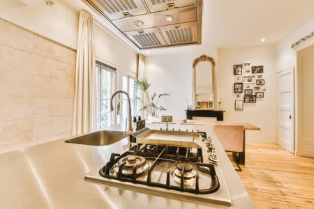 a kitchen with an oven on the stove top and wood flooring in the room behind it is a large windowの写真素材