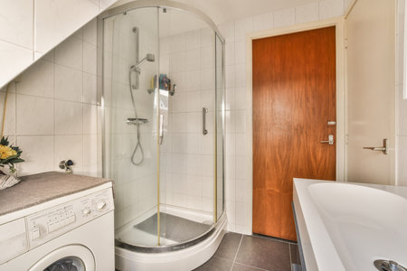 a bathroom with a washer and dryer next to the shower stall in front of the sink is white