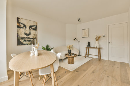 a living room with white walls and wood flooring in the center of the room is a dining table, two...