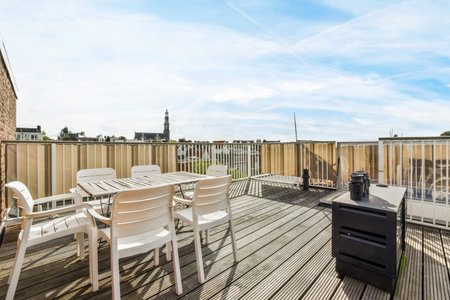 Amsterdam, Netherlands - 10 April, 2021: a deck with white chairs and an outdoor grill in the middle part of the deck there is a blue skyのeditorial素材