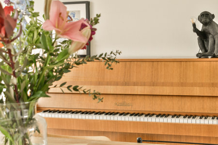 a cat sitting on top of a piano with flowers in front of it and a vase filled with pink liliesのeditorial素材