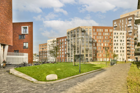 some buildings and grass in the middle of an urban area with people walking on either side of each other buildingsのeditorial素材