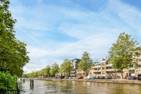 a river with buildings and trees in the fore, taken from a moving boat on its back sideのeditorial素材