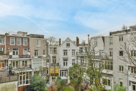 some houses with trees in the front yard and blue sky above them on a sunny day, as seen from an apartment balconyのeditorial素材