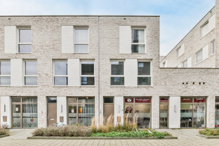 Amsterdam, Netherlands - 10 April, 2021: a brick building with many windows and plants on the ground in front of it, as seen from the sidewalkのeditorial素材