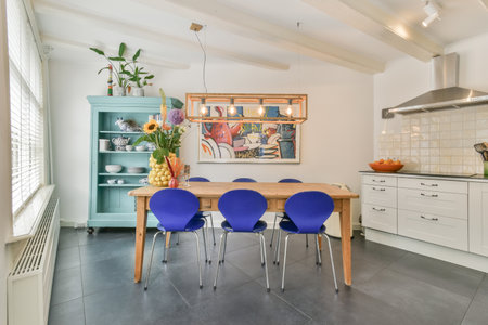 a kitchen with blue chairs and a wooden table in the center of the room is an artwork on the wall