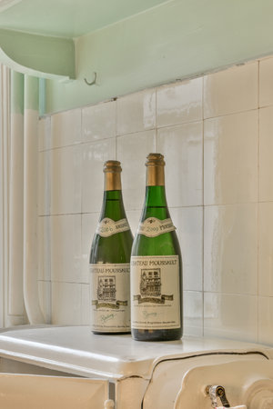 Amsterdam, Netherlands - 10 April, 2021: two bottles of beer sitting on top of a toaster in a white tile wall behind them is an old stoveのeditorial素材