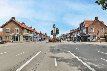 Amsterdam, Netherlands - 10 April, 2021: an empty street in the middle of a small town with houses and shops on both sides, under a bright blue skyのeditorial素材