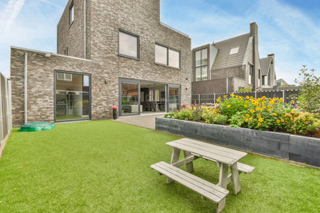 Amsterdam, Netherlands - 10 April, 2021: a backyard area with a bench and flowerbeds in the fore -...