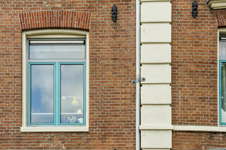 a building with two windows and a bird on the window sie in its right side, looking out to the leftのeditorial素材