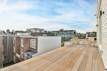 a wooden deck with buildings in the background and a blue sky overcasted by some white fluffy clouds aboveのeditorial素材
