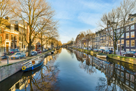 a canal in the middle of an urban area with houses and trees on either side of the water there is a blue sky aboveのeditorial素材