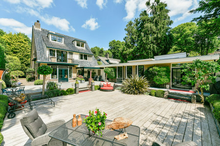Amsterdam, Netherlands - 10 April, 2021: a house from the outside with patio furniture and trees in the back yard, surrounded by lush green foliagesのeditorial素材