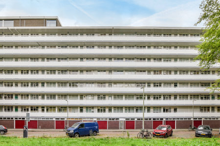 Amsterdam, Netherlands - 10 April, 2021: some cars parked in front of a large white building with red shutters on the windows and bale doorsのeditorial素材