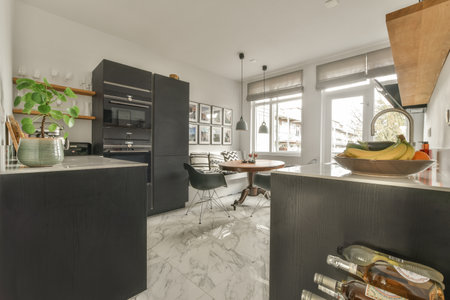 a kitchen with black cabinets and white marble flooring in the center of the room is an open space...