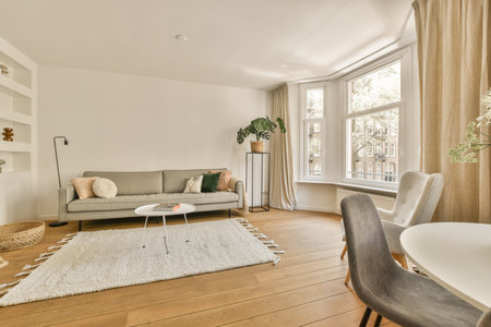 a living room with white walls and hardwood flooring, including a grey couch in the area has a large window that looks out ontoのeditorial素材