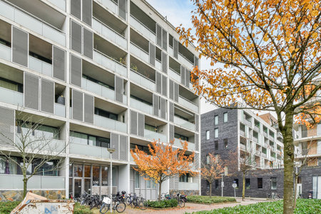 an apartment building with bicycles parked on the sidewalk and trees in front of themas new condo complexのeditorial素材