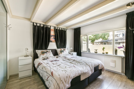 Amsterdam, Netherlands - 10 April, 2021: a bed in a bedroom with black curtains on the windows and white trim around the headboards that are hanging from the ceilingのeditorial素材