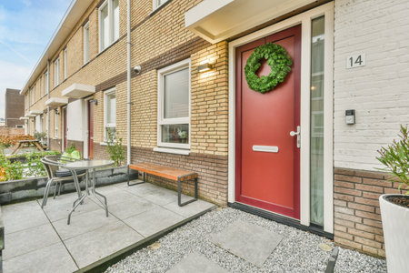 a red door on the side of a brick building with white trim around it and some potted plants in front