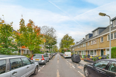 a street with cars parked on the side and houses in the back ground, some trees are turning their leavesのeditorial素材