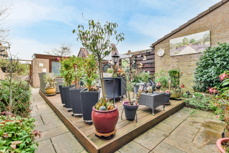 Amsterdam, Netherlands - 10 April, 2021: a patio with plants and pots on the ground in front of a brick wall behind it is a blue skyのeditorial素材