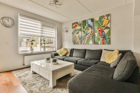 Amsterdam, Netherlands - 10 April, 2021: two parrots on the wall above a grey couch and white coffee...