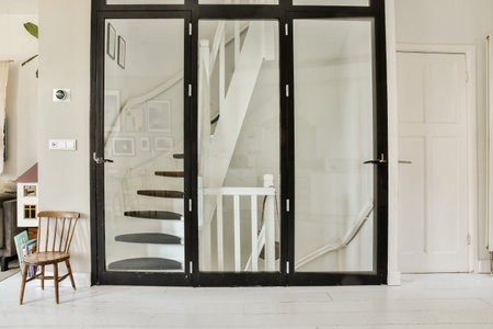 Amsterdam, Netherlands - 10 April, 2021: a living room with white walls and black glass doors that open up to the staircase leading into the dining areaのeditorial素材