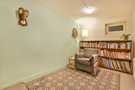 Amsterdam, Netherlands - 10 April, 2021: a living room with books on the shelves and a grey chair in front of a bookcase full of booksのeditorial素材