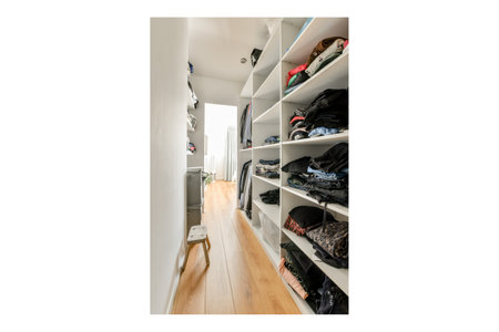 Amsterdam, Netherlands - 10 April, 2021: a walk - in closet with white shelvings and lots of clothes hanging on the wall next to itのeditorial素材