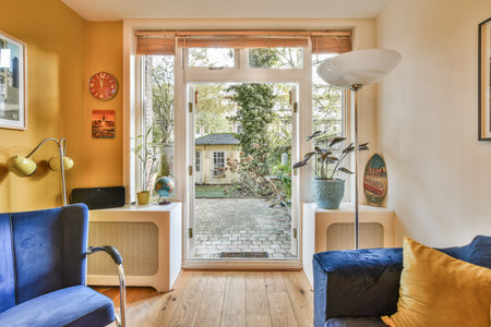 a living room with yellow walls and blue couches, an open door to the backyard garden is in the backgroundのeditorial素材