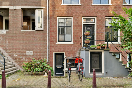 a bicycle parked in front of a building with plants growing out of the windows and steps leading up to itのeditorial素材