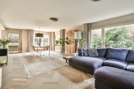 a living room with couches and a tv in the corner, looking out onto an outdoor patio area that is surrounded by treesのeditorial素材