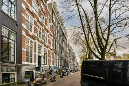 Amsterdam, Netherlands - 10 April, 2021: a city street with cars parked on the side and people walking down the sidewalk in front of some tall buildingsのeditorial素材