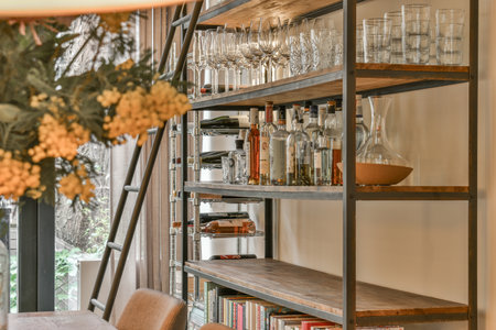 a book shelf with wine glasses on it and flowers in vases hanging from the ceiling over the bookshelのeditorial素材