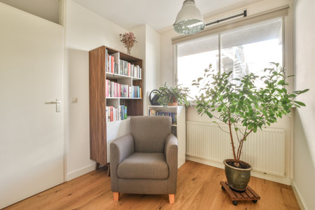 Amsterdam, Netherlands - 10 April, 2021: a living room with a chair and books on the shelf next to a plant in front of a bookcaseのeditorial素材