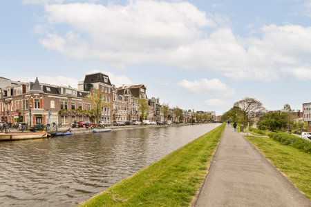 a canal with boats on the water and houses in the background, taken from a bike path along the waterwayのeditorial素材