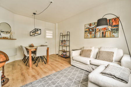 a living room with wood flooring and white couches in the room is decorated with decorative artwork on the wallのeditorial素材