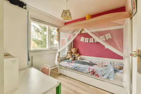 Amsterdam, Netherlands - 10 April, 2021: a childs room with pink walls and wooden flooring, including a white canopy over the bed that has a teddy bearのeditorial素材