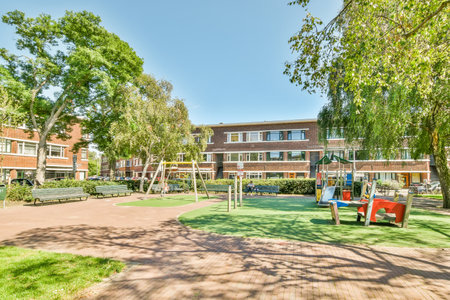 Amsterdam, Netherlands - 10 April, 2021: a childrens play area in the back yard at an apartment complex, with trees and lawns on both sidesのeditorial素材