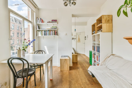 a living room with wood flooring and white walls there is a desk, chair, bookcases, bookshele