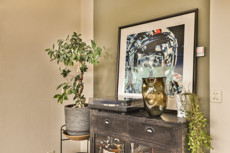 a woman is on the wall next to a potted plant in a black wooden cabinet with two metal legs