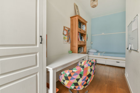 a small room with a desk, chair and bookshels on the wall next to the bed is an open doorのeditorial素材